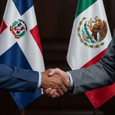Professional handshake between a Dominican and Mexican manufacturing representative with flags in the background, symbolizing the DR-CAFTA and Mexico electronics trade synergy.